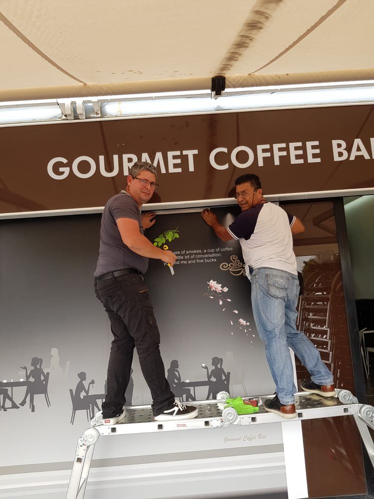Dos compañeros colocando vinilo en Gourmet Coffee Bar